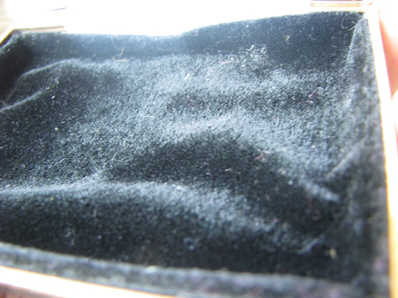 May include: A black velvet-lined box with a gold trim.