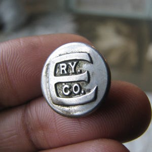 以下が含まれることがあります： 「E. RY. CO.」という文字が刻印された銀色の金属ボタンです。