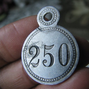 May include: A silver metal tag with a circular design and the number 250 embossed on the front.
