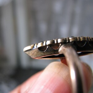 Puede incluir: Un anillo de oro con un dise&ntilde;o detallado y una banda lisa. El anillo est&aacute; engastado con una piedra preciosa redonda grande.