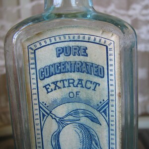 May include: A clear glass bottle with a blue and white label that reads "Pure Concentrated Extract of Lemon".