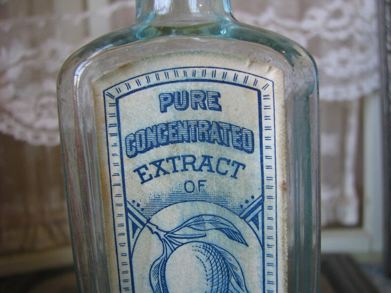 May include: A clear glass bottle with a blue and white label that reads "Pure Concentrated Extract of Lemon".