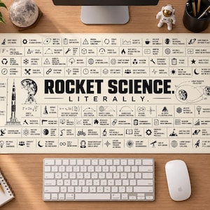 May include: A rectangular desk mat with a cream background and black text reading ROCKET SCIENCE. LITERALLY. The mat features a grid of small icons and phrases related to aerospace engineering, physics equations, and rocket diagrams.