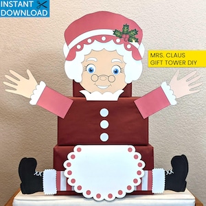 May include: A DIY Mrs. Claus gift tower. The design features a smiling Mrs. Claus face, arms, and legs, with a red dress and white apron. The gift tower is made of stacked red boxes. The text "MRS. CLAUS GIFT TOWER DIY" is visible.