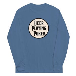 May include: A dusty blue long-sleeve crew neck shirt featuring a circular graphic on the chest. The graphic has a cream-colored background with a black border and the black text DEER PLAYING POKER centered inside in a bold, serif typeface.