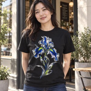 May include: A black short-sleeved t-shirt featuring a large, detailed graphic of a metallic-looking iris flower. The flower petals are rendered in shades of deep blue, silver, and bright yellow, creating a glossy, three-dimensional appearance.