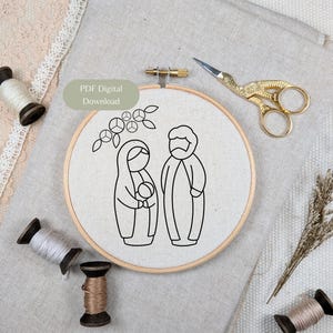 Peut inclure: Un tambour à broder rond en bois contenant un tissu blanc avec un motif au trait noir représentant une famille stylisée de trois personnes sous une branche fleurie. Le texte PDF Digital Download est visible. Des ciseaux cigogne dorés sont présents.