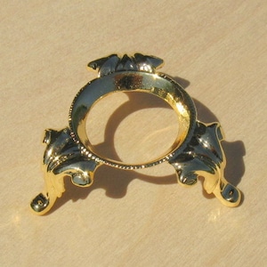 May include: Gold metal egg stand with a round top and three ornate legs.