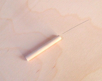 Puede incluir: Primer plano de una varilla de madera sobre una superficie de madera clara. La varilla de madera mide aproximadamente 15 cm de largo y tiene un acabado de madera natural.