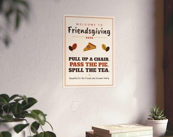 Puede incluir: Un póster de pared rectangular con fondo crema y un borde rojo fino. El texto dice: Welcome to Friendsgiving 2026. Pull up a chair. Pass the pie. Spill the tea. Thankful for the friends who became family. Incluye un icono de una porción de tarta.