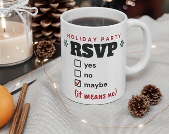 Puede incluir: Una taza de cerámica blanca con el texto HOLIDAY PARTY RSVP en rojo y negro, que incluye una lista de verificación con las opciones yes, no y maybe. Una marca roja está junto a maybe, con el texto rojo (it means no) debajo.