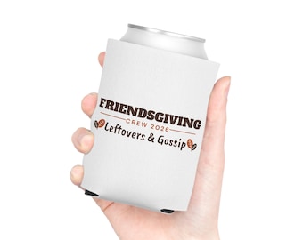 Puede incluir: Un enfriador de latas de espuma blanca con el texto en marrón FRIENDSGIVING CREW 2026 y Leftovers & Gossip, decorado con pequeñas ilustraciones de hojas marrones y naranjas a los lados del texto.