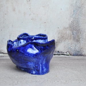 Peut inclure: Un pot en céramique bleu avec une forme organique unique. Le pot a une finition texturée et émaillée et semble être fait à la main.