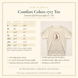 May include: An oat-colored Comfort Colors 1717 heavyweight t-shirt with a central graphic of a dog inside an oval frame. The image includes a size chart with measurements in inches for sizes S through 4XL, and lists product specifications.