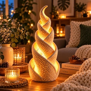 May include: A spiral-shaped table lamp with a textured, off-white crocheted exterior. The lamp emits a warm, internal glow through the intricate, perforated knit pattern, creating a conical, twisting structure that tapers to a point at the top.