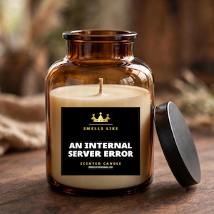 Peut inclure: Une bougie parfumée dans un pot en verre ambré avec un couvercle noir. L'étiquette noire porte le texte doré : SMELLS LIKE AN INTERNAL SERVER ERROR SCENTED CANDLE PRESS PERSONAL CO, avec une icône de couronne dorée et une mèche unique.