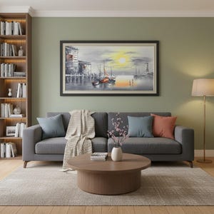 May include: A rectangular framed wall art piece depicting a harbor scene with a lighthouse, boats, and a bright yellow sun. The painting features a grayscale palette with accents of orange on the boats and the sun, set against a sage green wall.