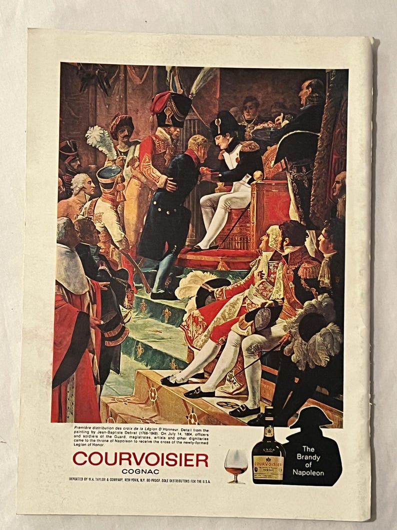 May include: An advertisement for Courvoisier Cognac featuring a historical painting of Napoleon. The image shows a scene of Napoleon bestowing honors, with a bottle of Courvoisier and a glass of cognac in the foreground. Text includes "The Brandy of Napoleon."