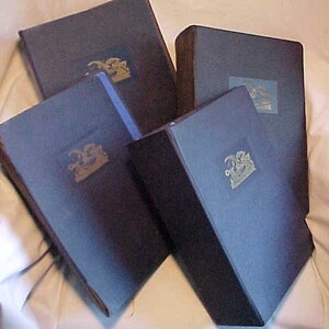 May include: Four navy blue hardcover books with gold lettering and illustrations on the front covers. The books are stacked on top of each other.