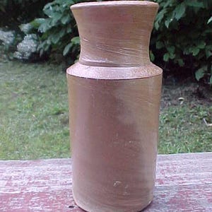 May include: A brown ceramic jar with a wide mouth and a rounded bottom. The jar has a smooth, slightly textured surface.