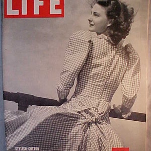 May include: A black and white photo of a woman wearing a gingham dress on the cover of LIFE magazine. The magazine cover is red with white text that reads "LIFE" and "MAY 8, 1939 10 CENTS".