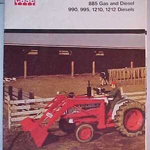 May include: A red Case David Brown tractor with a front loader attachment. The tractor is in a field with a wooden fence and a barn in the background. The text on the tractor reads "David Brown". The text on the brochure reads "Case David Brown Tractors 885 Gas and Diesel 990, 995, 1210, 1212 Diesels".
