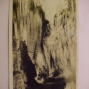 May include: A black and white photograph of the Queen's Room in Carlsbad Caverns, New Mexico. The photo shows a large cavern with many stalactites and stalagmites. The text "Queen's Room, Carlsbad Caverns (C) Ray V. Davis No. 181" is printed at the bottom of the photo.