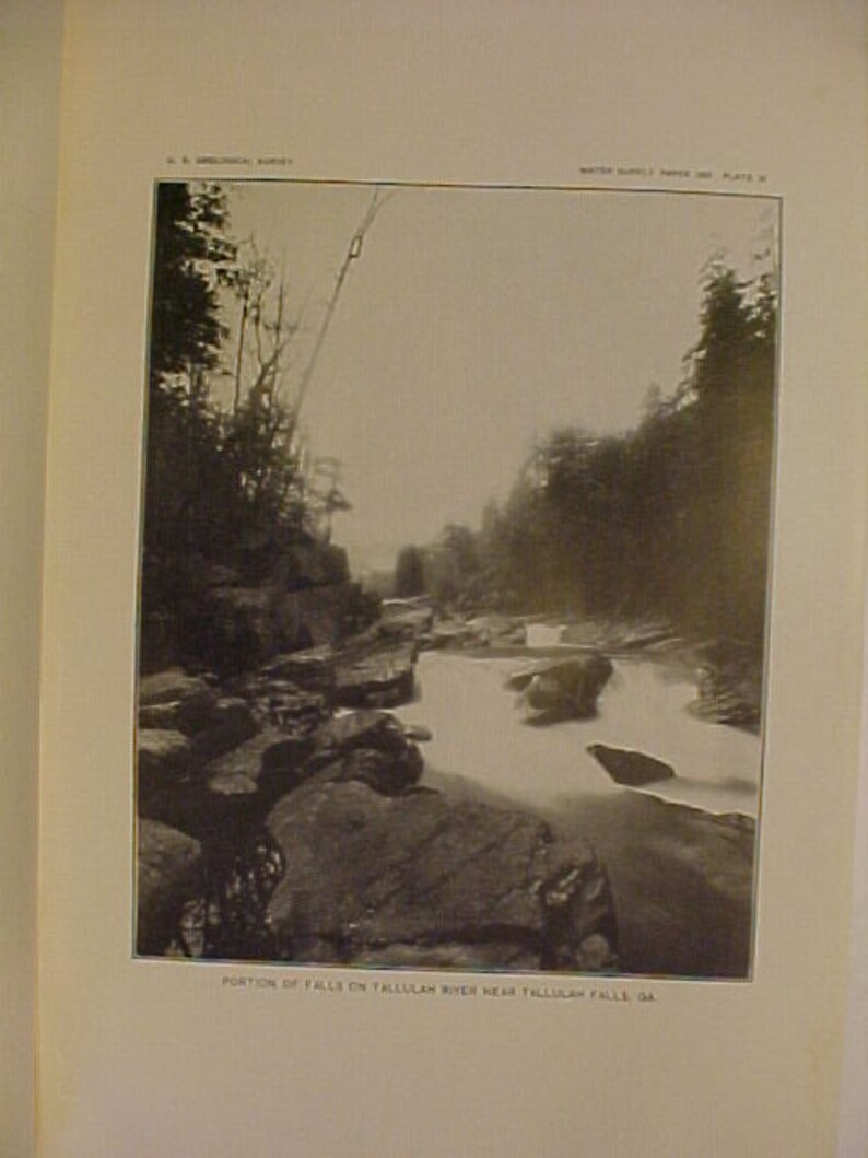 May include: A black and white photograph of a waterfall on the Tallulah River near Tallulah Falls, Georgia. The water cascades over rocks and creates a foamy white spray.