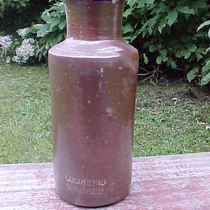May include: A brown stoneware jug with a wide mouth and a rounded body. The jug has a speckled glaze and the text "Glazena Brewer" is visible on the front.