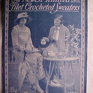 May include: A vintage book cover featuring two women wearing dresses. The cover is blue with white text that reads "The Newest Knitted and Filet Crocheted Sweaters" and "By Mary E. Fitch, Series No. 16".