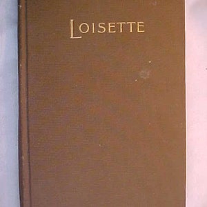 May include: A brown hardback book with the word "LOISETTE" embossed in gold on the front cover.