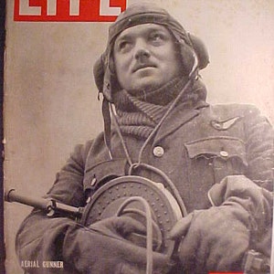 May include: A black and white photo of a man wearing a flight suit and a helmet. He is holding a machine gun and is looking up. The photo is from a LIFE magazine cover dated May 6, 1940. The text "AERIAL GUNNER" and "10 CENTS" are visible on the cover.