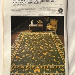 May include: An advertisement for a Chindia rug. The rug is green with yellow floral patterns and a yellow border. The text reads "IF LIFE'S GETTING TOO HARD FOR YOU, KEEP YOUR CHINDIA UP!" and includes information about the rug's quality and origin.