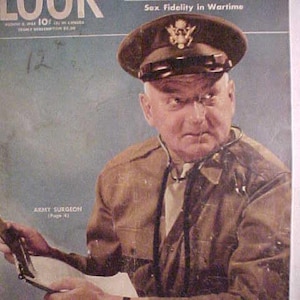May include: A vintage magazine cover featuring a man in a military uniform. The cover reads "LOOK" and "The Five Greatest Problems of the World" with the text "Sex Fidelity in Wartime" below. The man is wearing a brown uniform with a stethoscope around his neck. He is holding a document in his left hand and a pen in his right hand. The magazine cover is blue and white.
