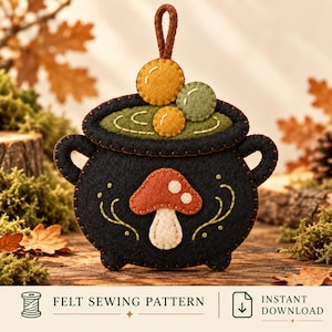 May include: A black felt cauldron ornament featuring a brown mushroom appliqué on the front, green felt liquid inside, and three small felt spheres on top. The item includes a brown hanging loop and the text FELT SEWING PATTERN INSTANT DOWNLOAD.