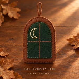 May include: A felt ornament shaped like an arched window with a dark green center and a brown border. The window features an embroidered crescent moon and a cross-shaped frame. Text below reads: FELT SEWING PATTERN INSTANT DOWNLOAD.