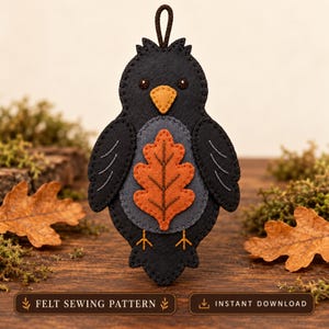Puede incluir: Un adorno de fieltro negro con forma de pájaro, vientre gris, aplicación de hoja de roble naranja, pico amarillo y detalles bordados. El adorno tiene un lazo marrón para colgar. Texto inferior: FELT SEWING PATTERN INSTANT DOWNLOAD.