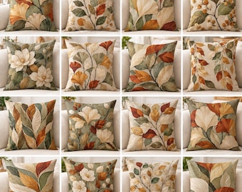 Puede incluir: Una colección de dieciséis cojines cuadrados con estampados botánicos de hojas de ginkgo, flores de magnolia y follaje otoñal en tonos crema, verde salvia, naranja quemado y marrón sobre un fondo de tela texturizada.
