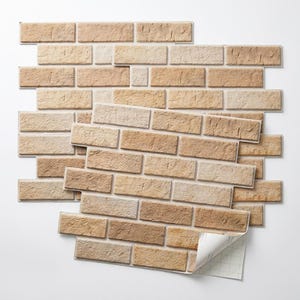 May include: A set of rectangular wall tiles featuring a realistic tan and beige brick pattern with a textured surface. The tiles are arranged in an overlapping stack, with one corner of the top tile peeled back to reveal a white adhesive backing.