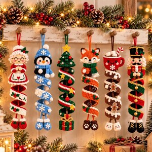 May include: Six crocheted Christmas ornaments hanging in a row. The figures include a woman in a red dress, a blue penguin, a green Christmas tree, an orange fox, a red mug with marshmallows, and a nutcracker, all with spiral tails.