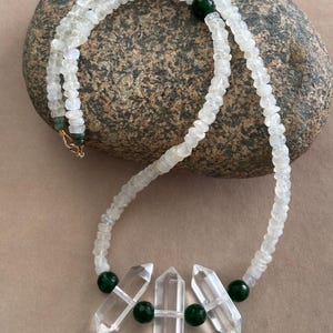 Pode incluir: Um colar de contas de pedra da lua branca com três pontas de cristal de quartzo transparente e contas de jade verde.