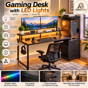May include: A black gaming desk with a monitor stand, three fabric storage drawers, and a metal frame. It features integrated RGB LED lighting, three AC outlets, and two USB ports. The desk includes a computer tower shelf and a headphone hook.