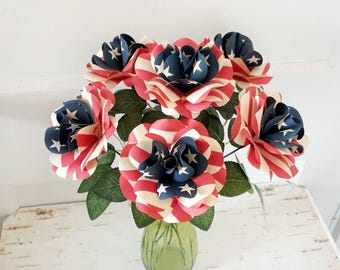 Könnte beinhalten: Ein Strauß roter, weißer und blauer Papierrosen. Die Rosen sind mit dem Muster der amerikanischen Flagge verziert. Die Rosen stehen in einer grünen Vase.
