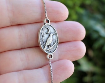 Pulsera de plata con cuervo y luna, joyería gótica de inspiración natural y mística.
