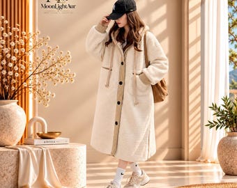 May include: A long, cream-coloured fleece coat with a hood, a button-down front, and tan trim. The coat features long sleeves, side pockets, and a textured finish. It is paired with a black baseball cap, white socks, and light-coloured trainers.