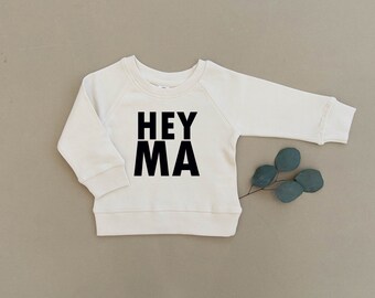 May include: White long-sleeved sweatshirt with black text that reads "HEY MA".