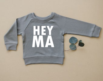 May include: A gray sweatshirt with the text "HEY MA" printed in white on the front.