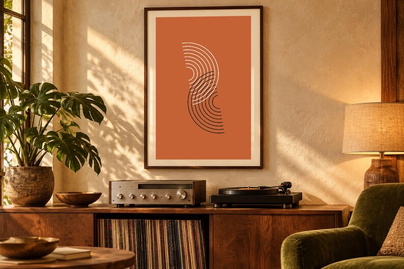 May include: A framed wall art print featuring a burnt orange background with two overlapping vertical semi-circles composed of thin white and black concentric lines, displayed in a dark wood frame on a textured wall.