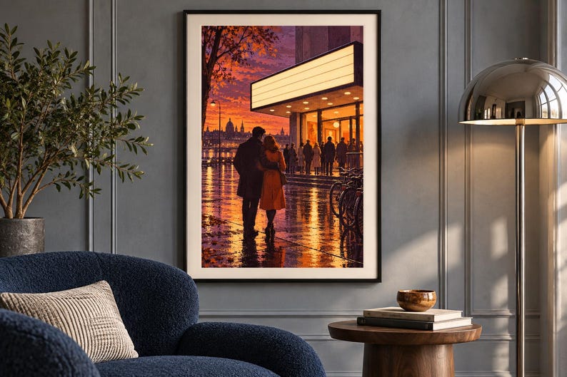 May include: A framed wall art print depicting a couple standing before a brightly lit theater marquee at sunset. The scene features a wet city street reflecting warm orange and purple sky colors, with silhouettes of people and bicycles nearby.