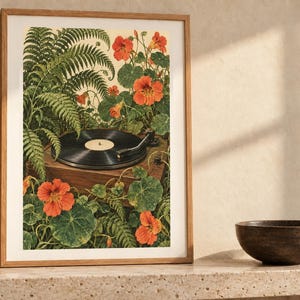 Puede incluir: Una l&aacute;mina de arte enmarcada que muestra un tocadiscos de vinilo negro rodeado de frondosos helechos verdes y flores de capuchina de color naranja vibrante. La ilustraci&oacute;n representa un tocadiscos de madera entre un denso follaje bot&aacute;nico.